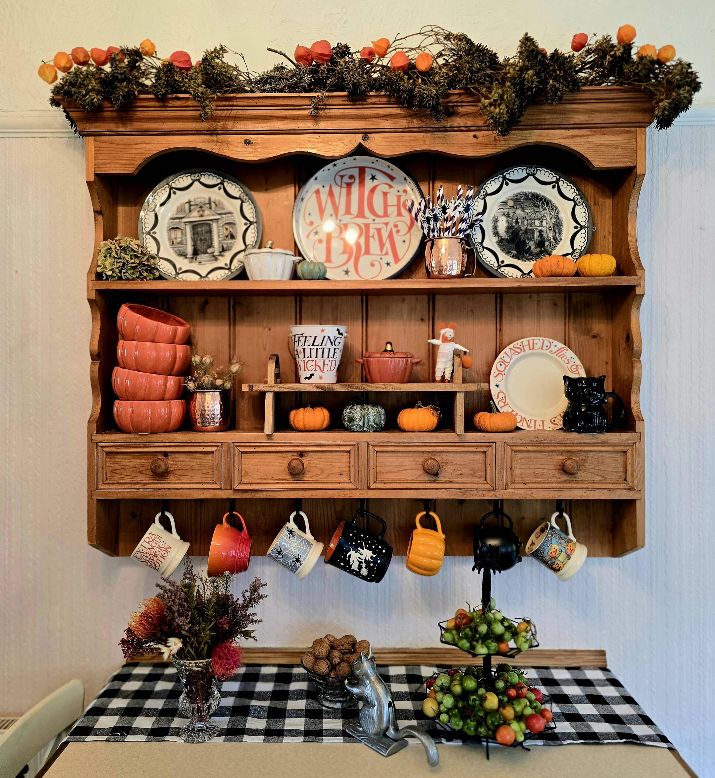 A dresser filled with halloween inspired mugs. Plates and curios